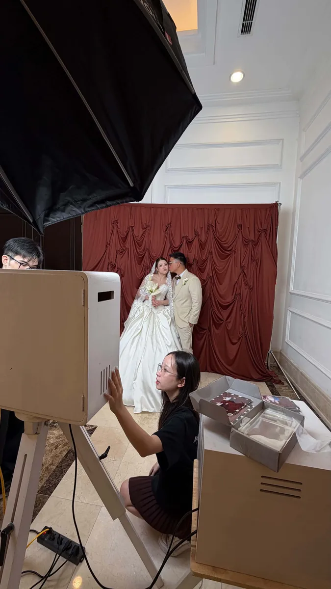 Cô dâu chú rể chụp ảnh, nhân viên hướng dẫn trên màn hình booth