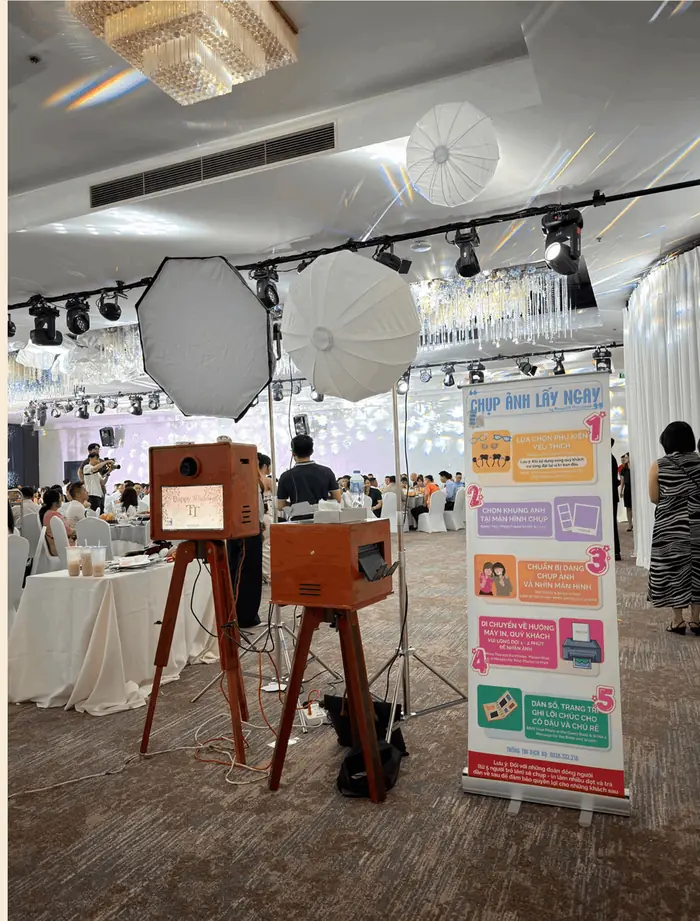 Booth gỗ, máy in và đèn studio dựng trong sảnh tiệc